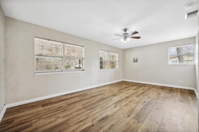 empty room featuring ceiling fan, hardwood / wood-style floors, and a wealth of natural light