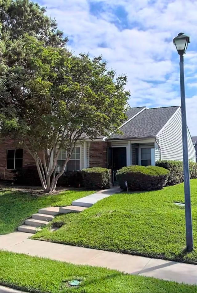 view of front of property featuring a shingled roof and a front yard