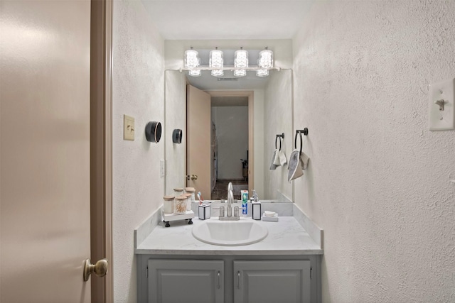 bathroom with a textured wall and vanity