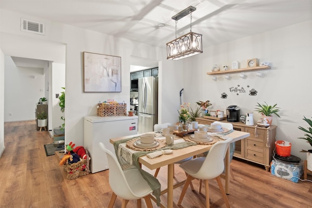 dining room with a notable chandelier and light wood-type flooring