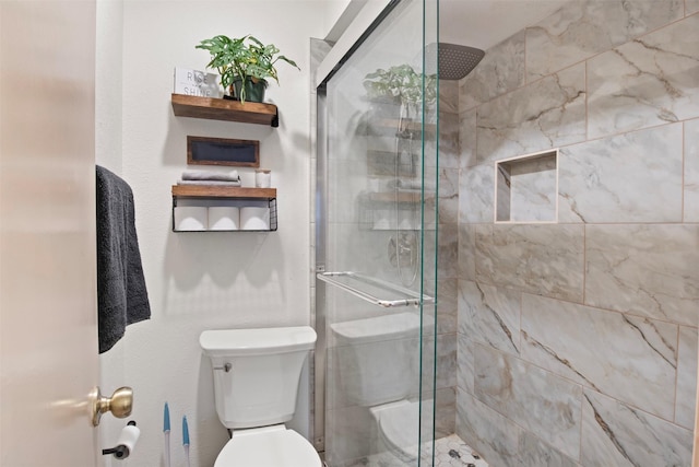 bathroom featuring a shower with door and toilet