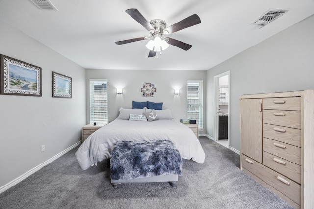 bedroom featuring multiple windows, ensuite bathroom, dark carpet, and ceiling fan