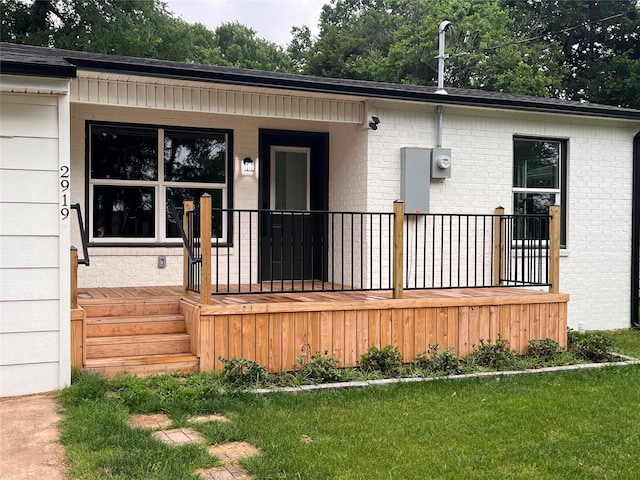 entrance to property featuring a porch and a lawn