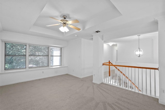 spare room with light carpet, ceiling fan with notable chandelier, ornamental molding, and a raised ceiling