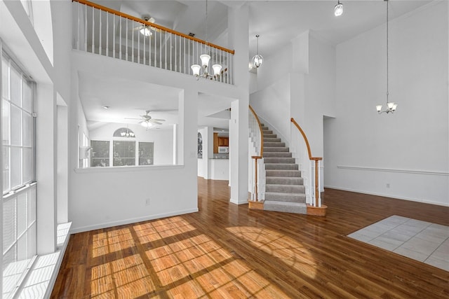 unfurnished living room featuring a healthy amount of sunlight, wood-type flooring, and a high ceiling