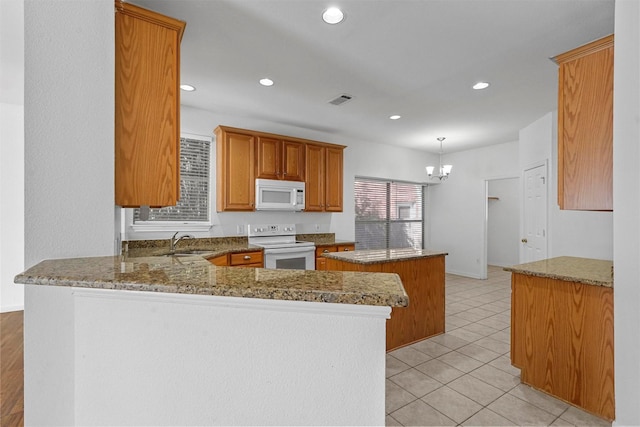 kitchen with a kitchen island, stone countertops, decorative light fixtures, kitchen peninsula, and white appliances