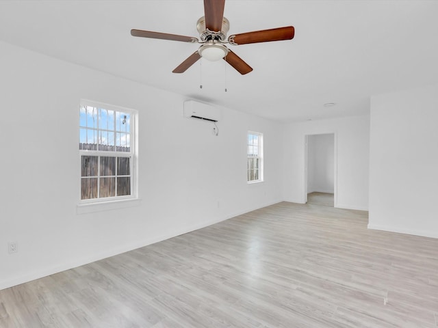 empty room featuring light hardwood / wood-style flooring, a wall mounted air conditioner, plenty of natural light, and ceiling fan