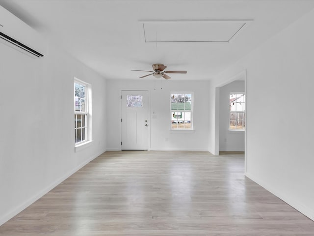 interior space featuring a wall mounted air conditioner, light hardwood / wood-style flooring, and ceiling fan