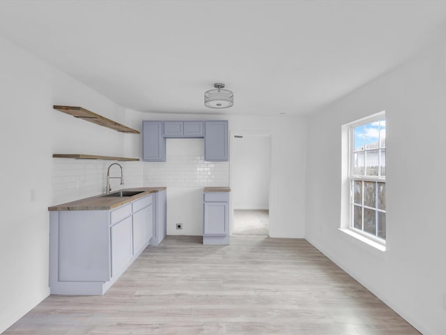 kitchen with light hardwood / wood-style flooring, sink, decorative backsplash, and gray cabinetry