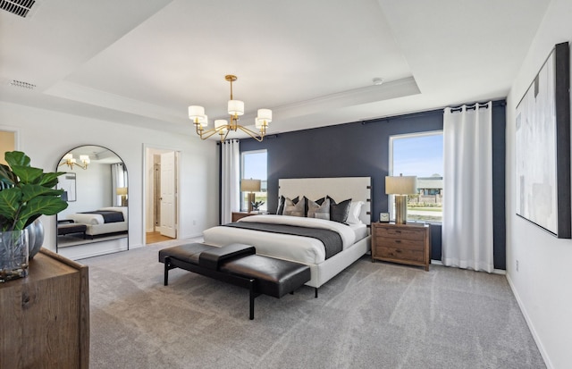 bedroom with a tray ceiling, light colored carpet, a chandelier, and ensuite bathroom