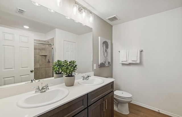 bathroom with hardwood / wood-style flooring, vanity, toilet, and a shower with shower door