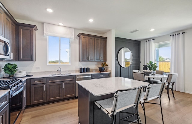 kitchen featuring sink, a center island, light wood-type flooring, a wealth of natural light, and stainless steel appliances