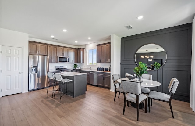 kitchen with sink, a breakfast bar, an inviting chandelier, stainless steel appliances, and a center island