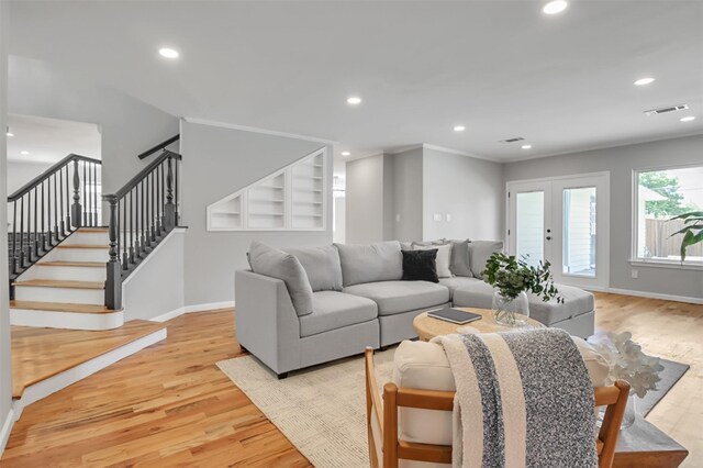 living room featuring ornamental molding, french doors, and light wood-type flooring