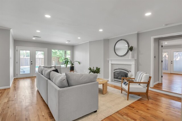 living room featuring french doors, ornamental molding, light hardwood / wood-style floors, and built in shelves