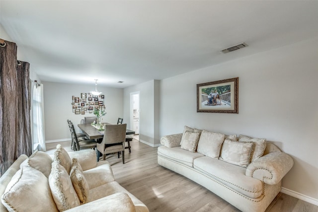 living room featuring an inviting chandelier, light hardwood / wood-style flooring, and a healthy amount of sunlight