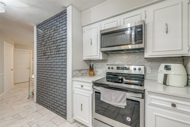 kitchen with white cabinetry, stainless steel appliances, and backsplash