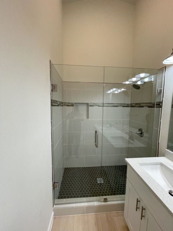 bathroom featuring vanity, a shower with shower door, and wood-type flooring