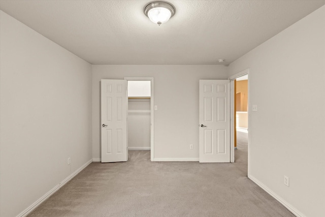 unfurnished bedroom with a spacious closet, light carpet, and a closet