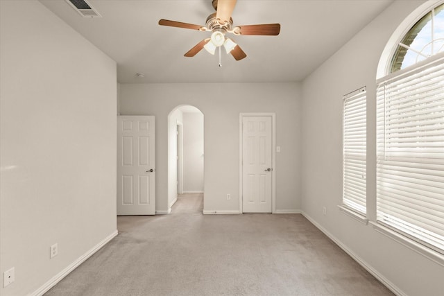 carpeted spare room with ceiling fan and plenty of natural light