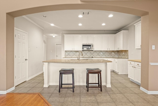 kitchen featuring a kitchen island with sink, white cabinets, and light tile patterned flooring