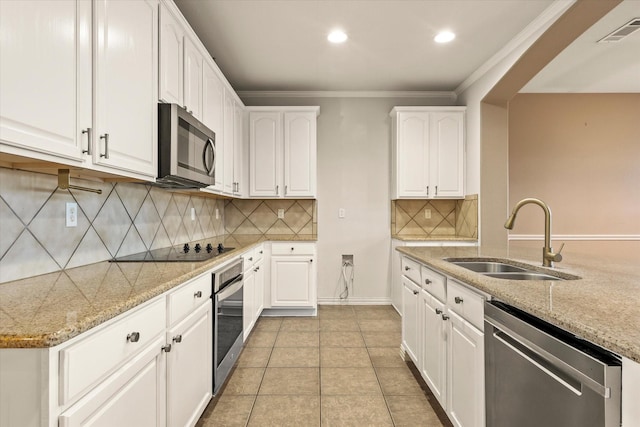 kitchen with appliances with stainless steel finishes, white cabinetry, sink, light tile patterned floors, and light stone countertops