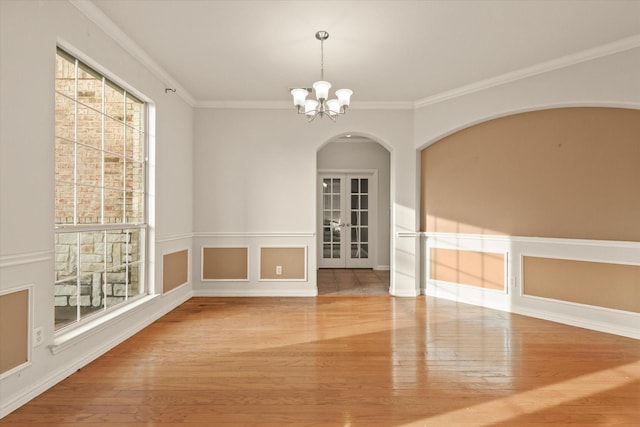 unfurnished dining area with an inviting chandelier, ornamental molding, and wood-type flooring