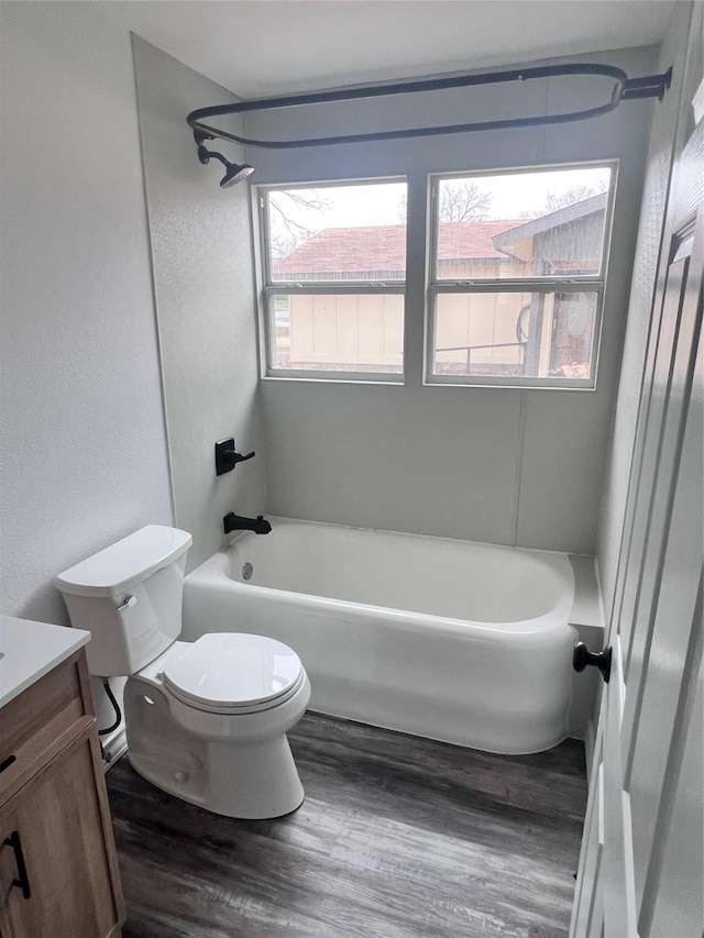 full bathroom with hardwood / wood-style flooring, washtub / shower combination, vanity, and toilet