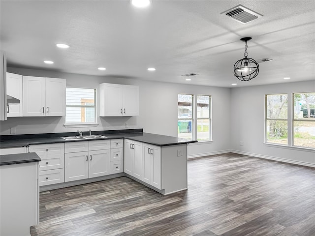 kitchen featuring pendant lighting, plenty of natural light, sink, and white cabinets