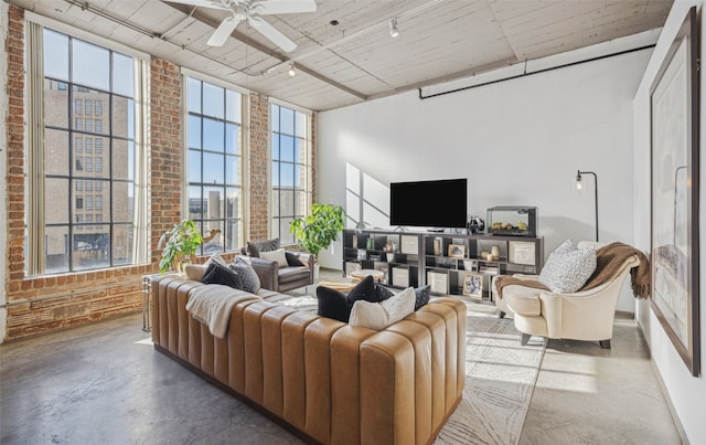 living room featuring ceiling fan, track lighting, brick wall, and concrete flooring