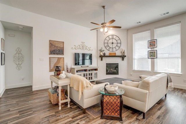 living room featuring dark hardwood / wood-style flooring, a fireplace, and ceiling fan