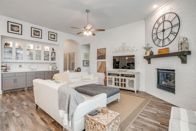 living room with ceiling fan, a fireplace, and dark hardwood / wood-style flooring