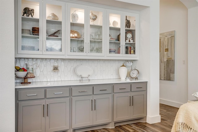 bar with gray cabinetry, backsplash, and dark hardwood / wood-style floors