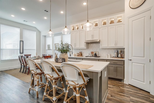 kitchen with pendant lighting, white cabinetry, tasteful backsplash, a center island with sink, and stainless steel gas stovetop