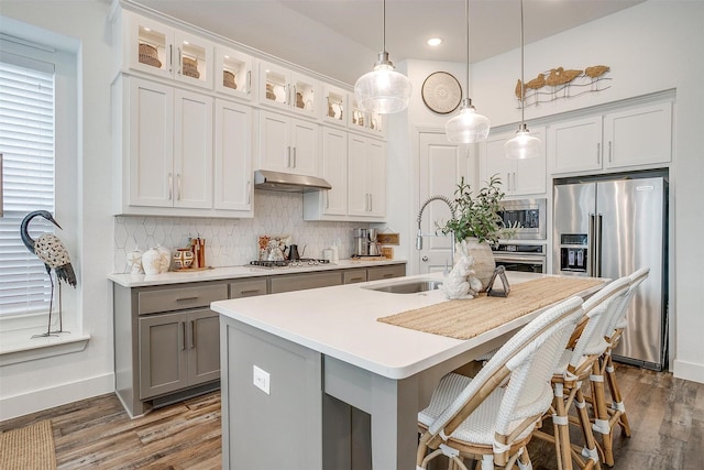 kitchen with tasteful backsplash, an island with sink, appliances with stainless steel finishes, and pendant lighting