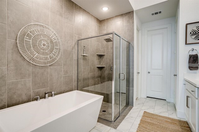 bathroom featuring shower with separate bathtub, tile walls, and vanity