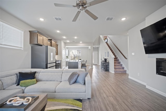 living room featuring ceiling fan, sink, and light hardwood / wood-style floors