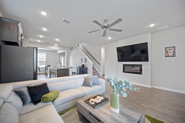 living room featuring sink, hardwood / wood-style flooring, and ceiling fan