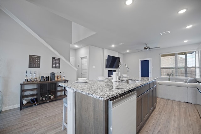 kitchen featuring sink, dishwasher, an island with sink, ceiling fan, and light hardwood / wood-style floors