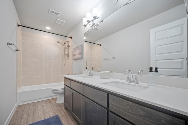 full bathroom featuring vanity, hardwood / wood-style flooring, tiled shower / bath combo, and toilet