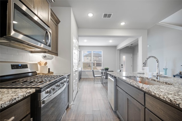 kitchen with light stone counters, stainless steel appliances, sink, and decorative backsplash