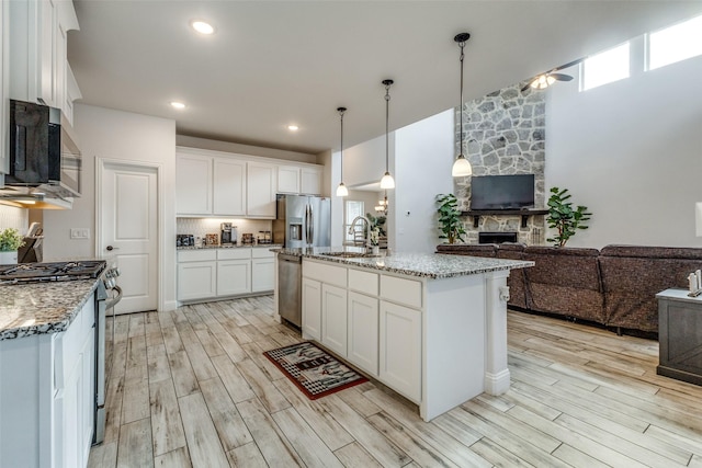 kitchen featuring sink, white cabinetry, a center island with sink, pendant lighting, and stainless steel appliances