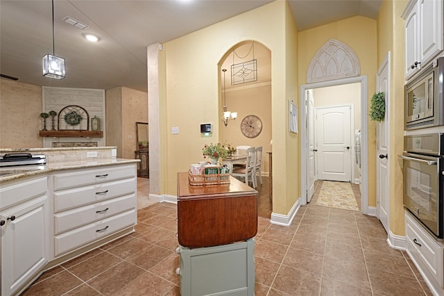 kitchen with hanging light fixtures, appliances with stainless steel finishes, dark tile patterned floors, and white cabinets