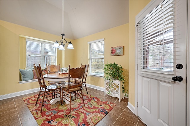 dining area featuring lofted ceiling, dark tile patterned floors, a chandelier, and baseboards