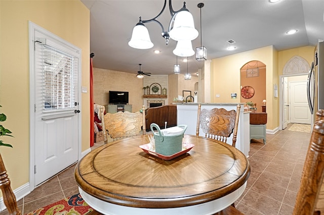 tiled dining area featuring a large fireplace and ceiling fan