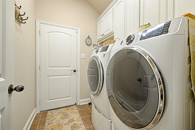 laundry room featuring light tile patterned floors, washing machine and dryer, cabinet space, and baseboards