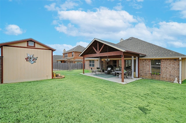 rear view of property featuring a patio, brick siding, fence, a lawn, and roof with shingles