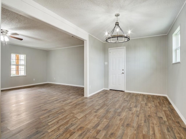 spare room with ornamental molding, ceiling fan with notable chandelier, a textured ceiling, and dark hardwood / wood-style flooring