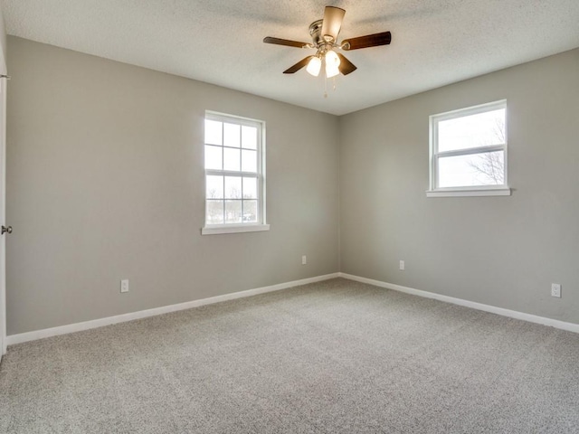 carpeted spare room with plenty of natural light, a textured ceiling, and ceiling fan