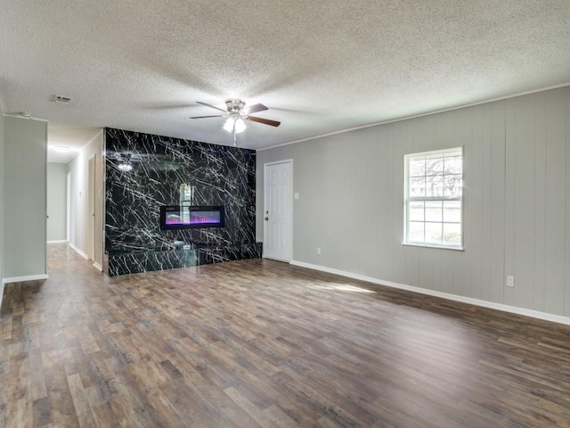 unfurnished living room with a high end fireplace, dark wood-type flooring, a textured ceiling, and ceiling fan